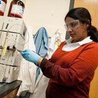 A student wearing safety glasses and gloves while working with lab equipment.